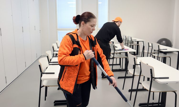 Kaksi henkilöä siivoavat luokkatilaa